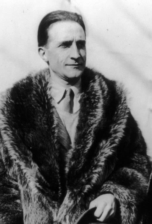 Pintura abstrata em tons de azul e cinza, retratando a silhueta de Marcel Duchamp sentado em uma cadeira, com objetos surreais ao redor.