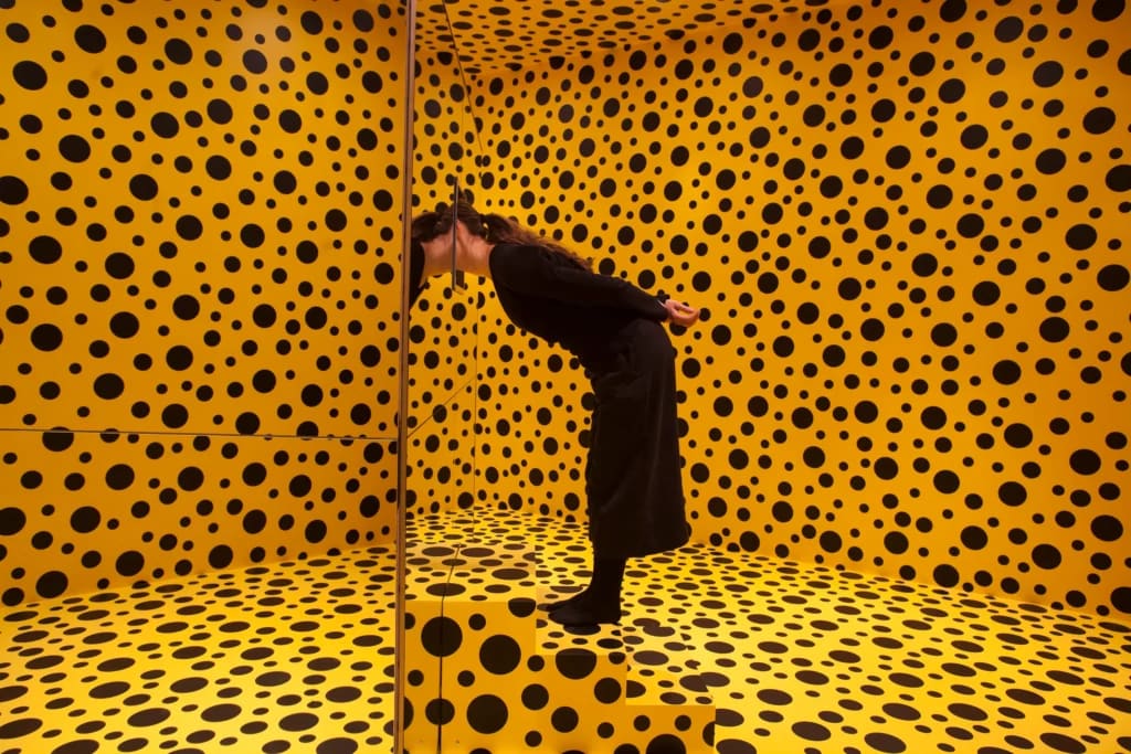Yayoi Kusama en medio de una instalación de puntos infinitos